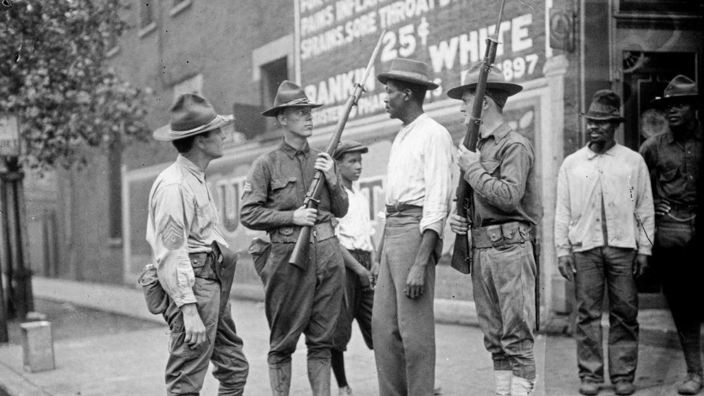 Armed National Guard and African American men standing on a sidewalk during the race riots in Chicago, Illinois, 1919.