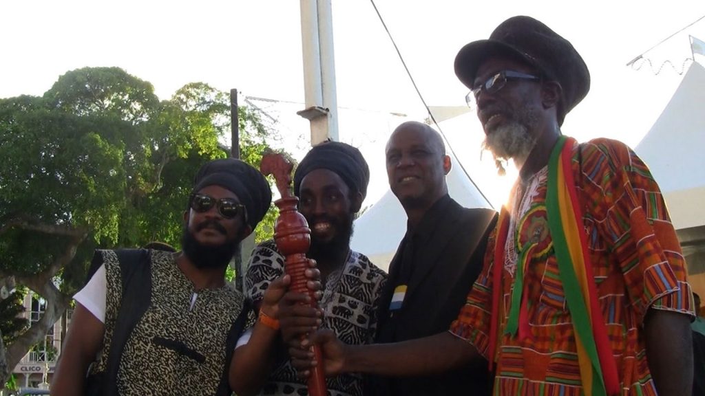 Ras Bongo Wisely Tafari (far right) holds on to the CARICOM’s symbol of the reparatory justice movement, the reparations baton, in Castries, Saint Lucia.