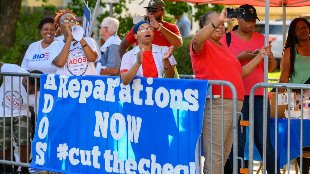 American Descendants of Slavery (ADOS) activists demand reparations for slavery outside a 2019 Democratic event.
