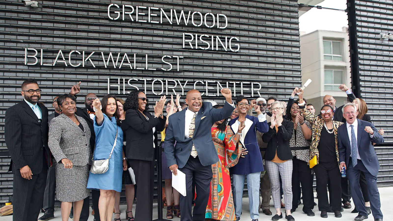 Members of the 1921 Tulsa Race Massacre Centennial Commission, with State Sen. Kevin Matthews in front, cheer in front of the Greenwood Rising Black Wall St. History Center before a dedication in June 2021 in Tulsa. (Mike Simons/Tulsa World/AP)Members of the 1921 Tulsa Race Massacre Centennial Commission, with State Sen. Kevin Matthews in front, cheer in front of the Greenwood Rising Black Wall St. History Center before a dedication in June 2021 in Tulsa.